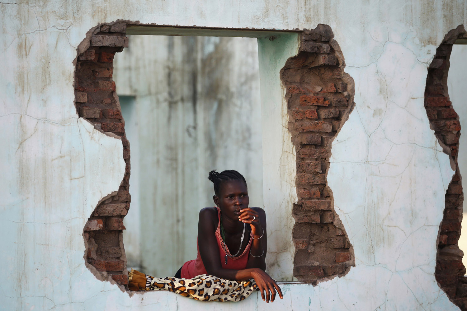 Oct. 26, 2013. A woman looks out of an abandoned building near polling stations in the town of Abyei, ahead of the referendum on whether to join Sudan or South Sudan.