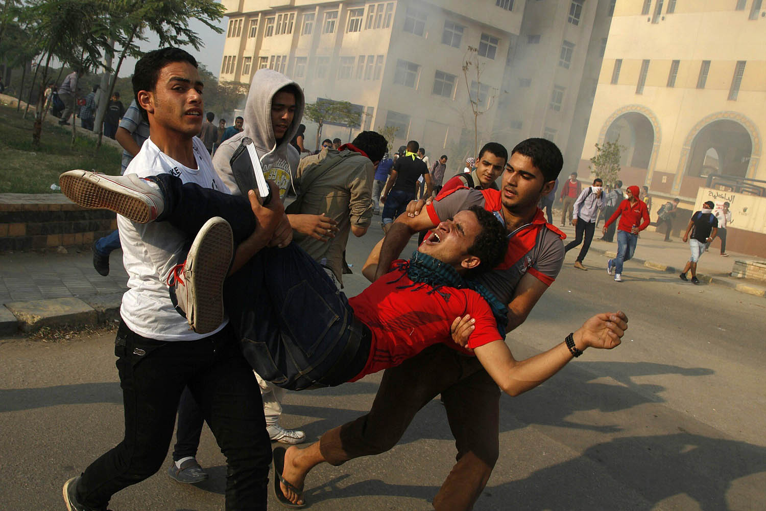 Oct. 28, 2013. Student supporters of ousted president Mohamed Morsi and the Muslim brotherhood carry a comrade injured during clashes with Egyptian security forces outside al-Azhar university in Cairo, Egypt.