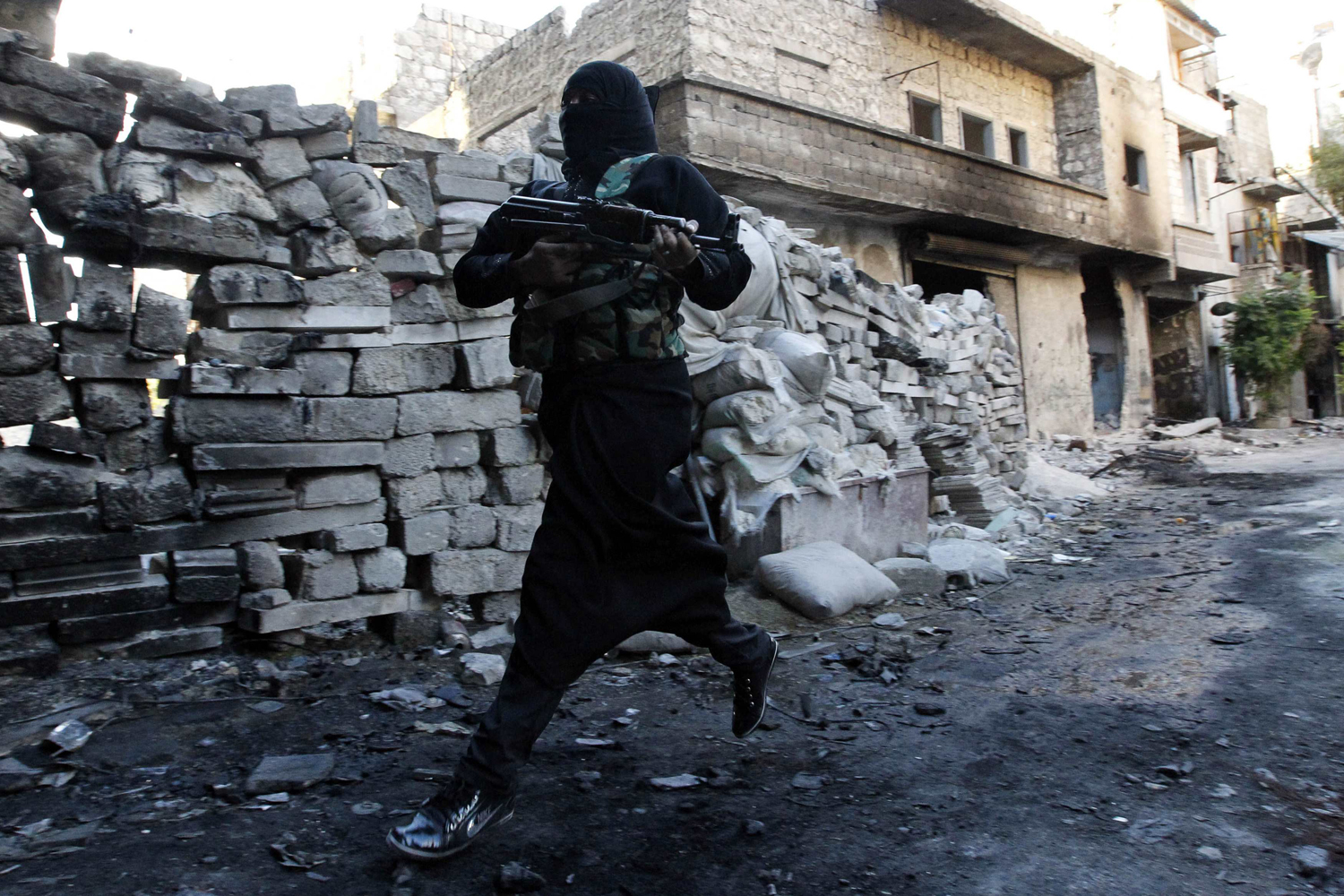 Oct. 3, 2013. Um Radwan, a female fighter in the Free Syrian Army, runs for cover from snipers loyal to the Syrian regime in Aleppo's Bustan al-Basha district.