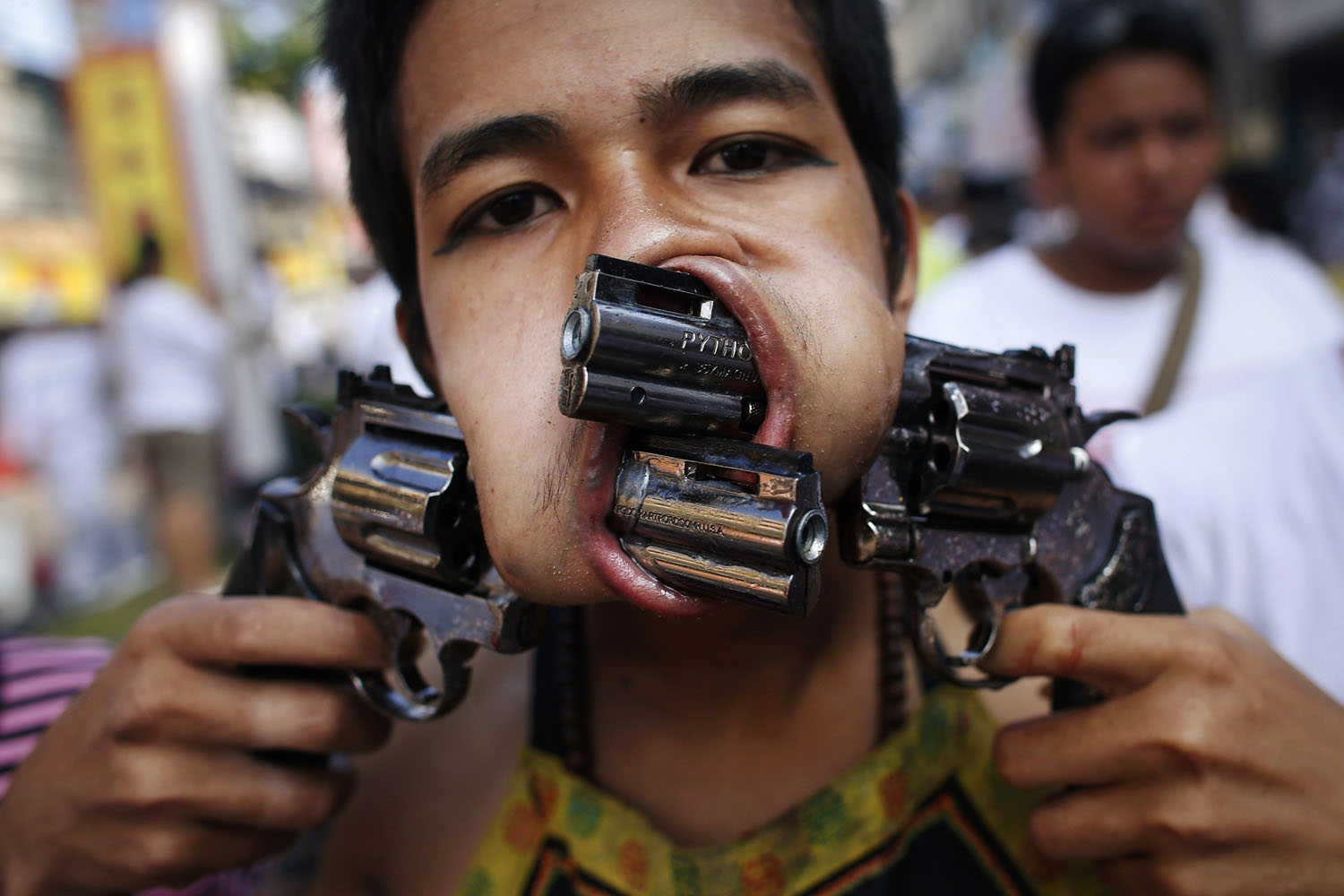 A devotee, with two guns pierced through his cheeks, takes part in a street procession during the annual vegetarian festival in Phuket