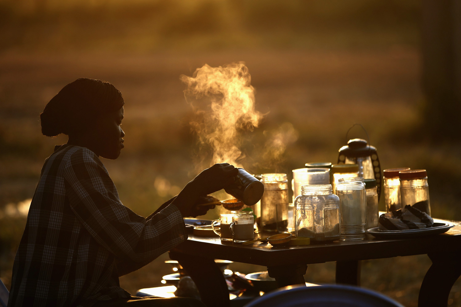 A woman prepares tea at an outdoor coffee shop near a polling station located in a school during a referendum in the town of Abyei