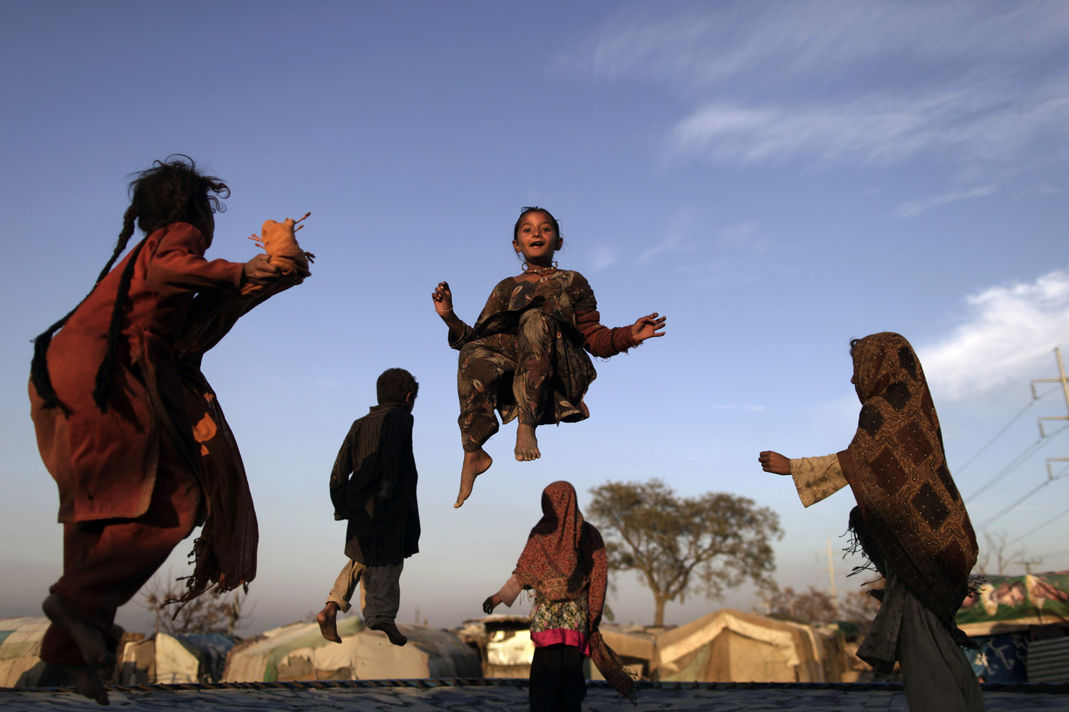 Feb. 8, 2013. Pakistani children, who were displaced with their families by 2010 floods from a village in Pakistan's Sindh province, enjoy jumping on a trampoline in an Islamabad slum.