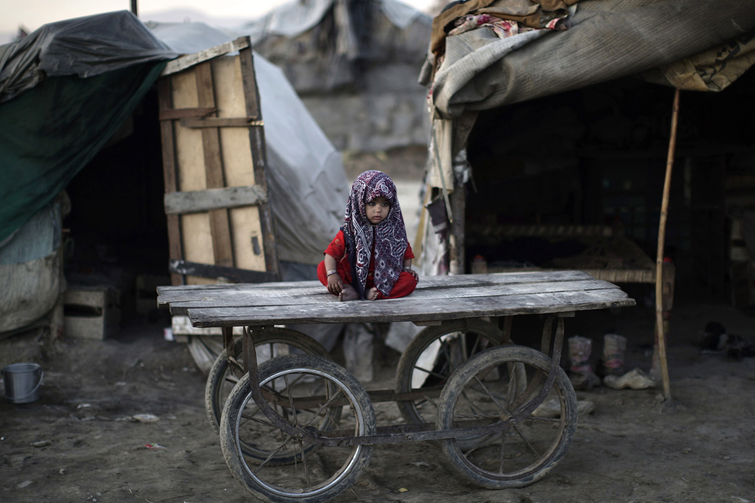 Feb. 8, 2013. A Pakistani child sits on a wooden cart outside her family's makeshift home on the outskirts of Islamabad.