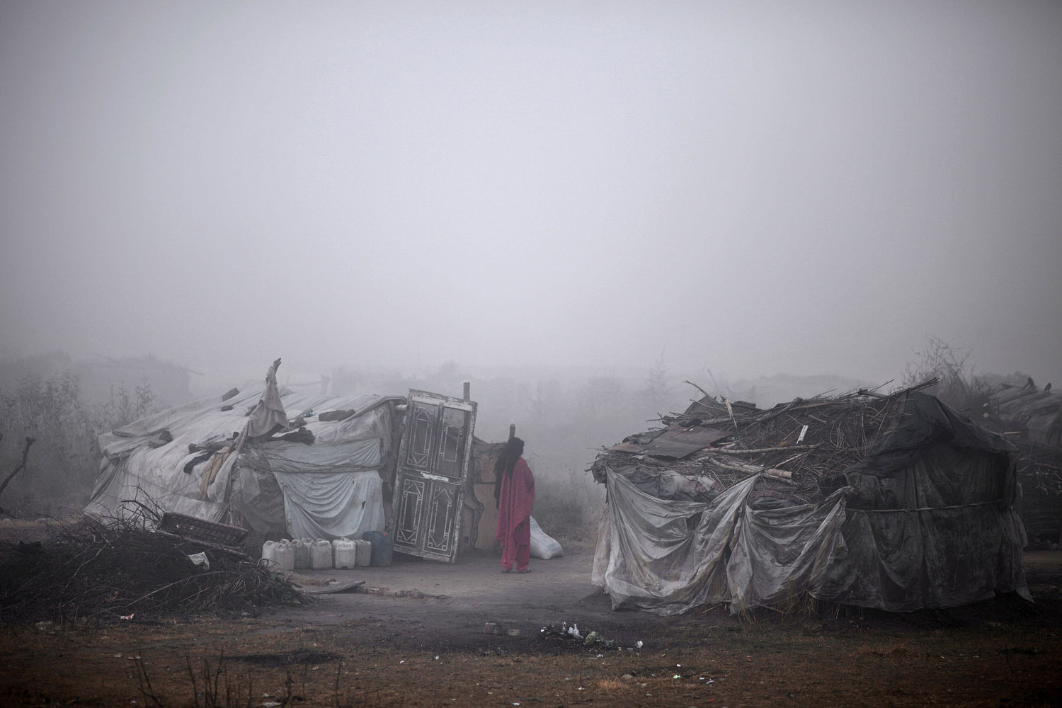 Jan. 4, 2013. A Pakistani woman stands outside her makeshift home in a slum during a foggy and cold morning in Islamabad.