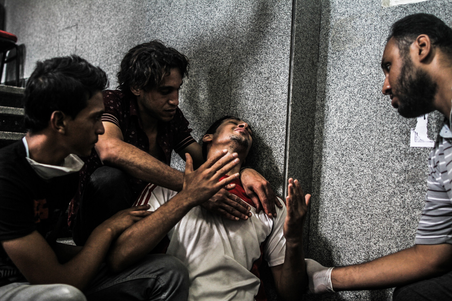 A brother of one of the victims is comforted by friends outside the room being used as a makeshift morgue.