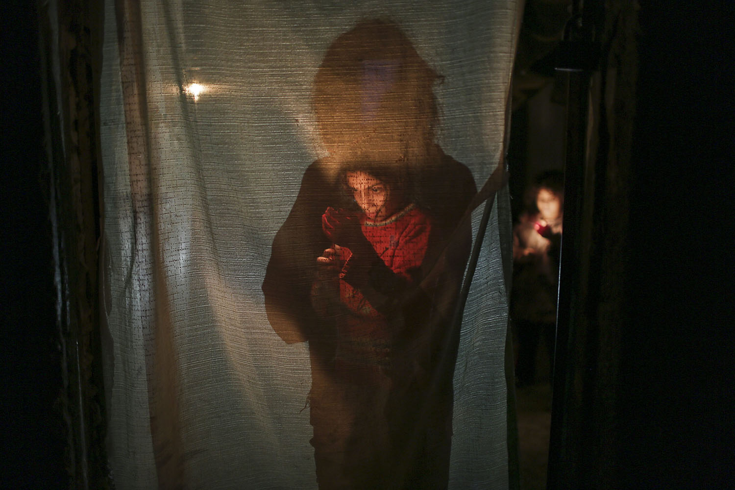 Nov. 18, 2013. A Palestinian girl holds a candle inside her family's house during a power cut in Jabaliya refugee camp, in northern Gaza Strip.
