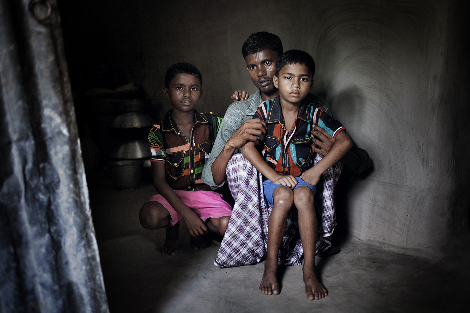 June 2, 2013. Parvej, 7, and Palash, 5, sons of missing worker Rehana, and her husband Jahedul at their home in Joypur Hat, Bangladesh.