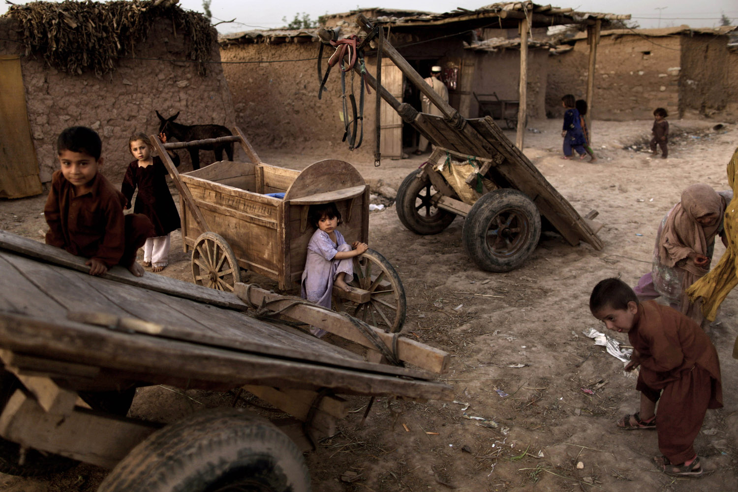 April 11, 2013. Afghan refugee children play around wooden carts left in a poor neighborhood on the outskirts of Islamabad.