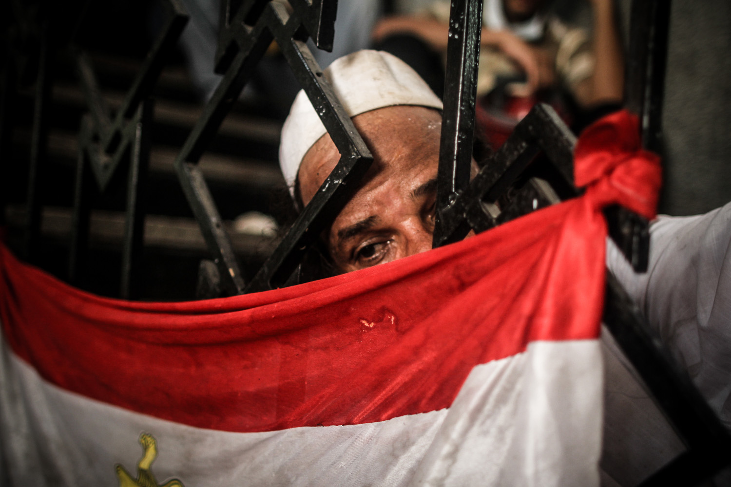A man grieves next to a flag outside the makeshift morgue of Rabaa Adaweya where bodies killed during the violent dispersal of the camp where kept. August 14, 2013.