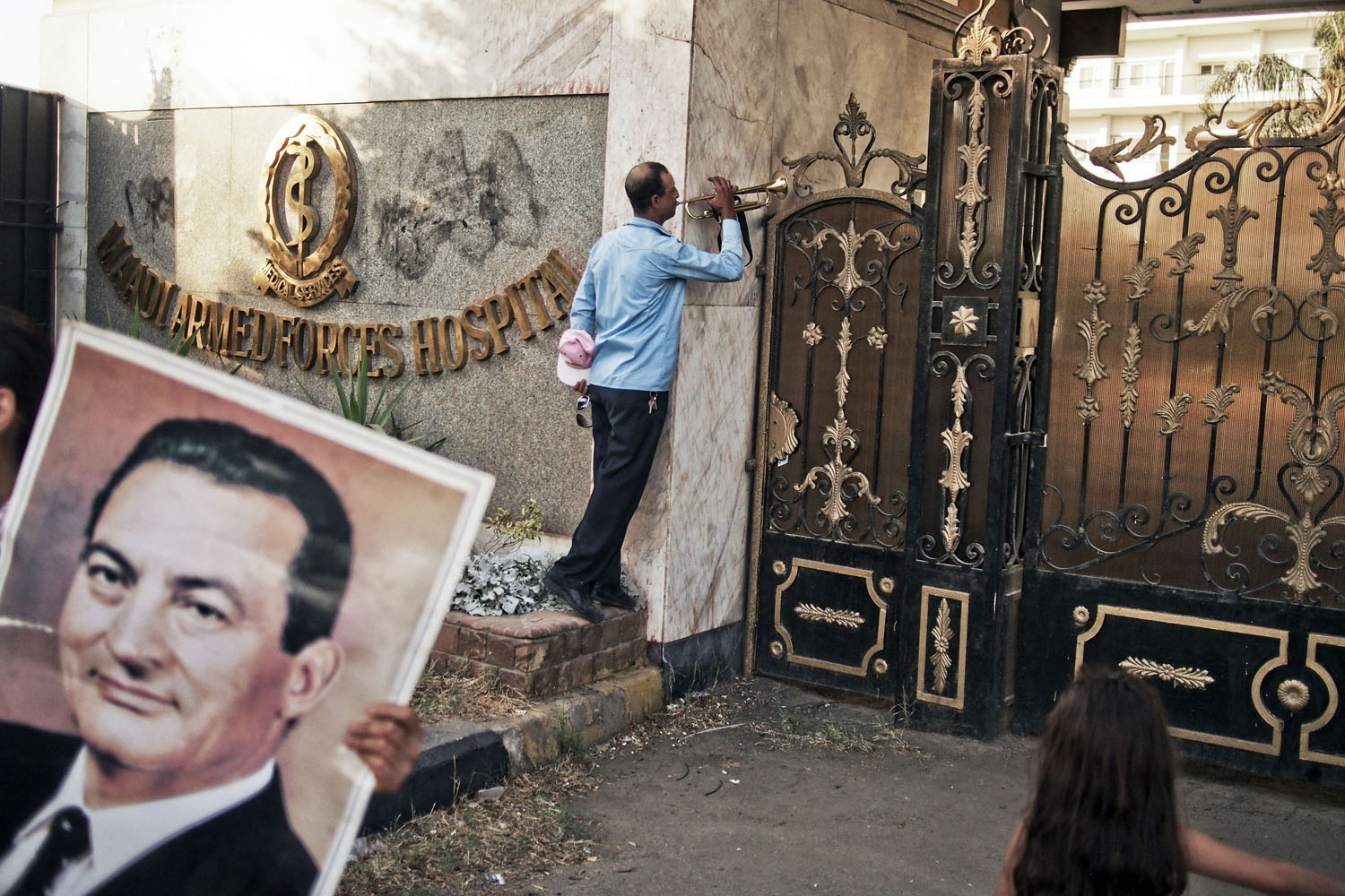 EGYPT. Cairo. August 22, 2013. A supporter of former Egyptian President Hosni Mubarak plays the trumpet at the gates of the Maadi Military Hospital where Mr. Mubarak was admited after being released from Tora Prison on the outskirts of Cairo, Thursday.