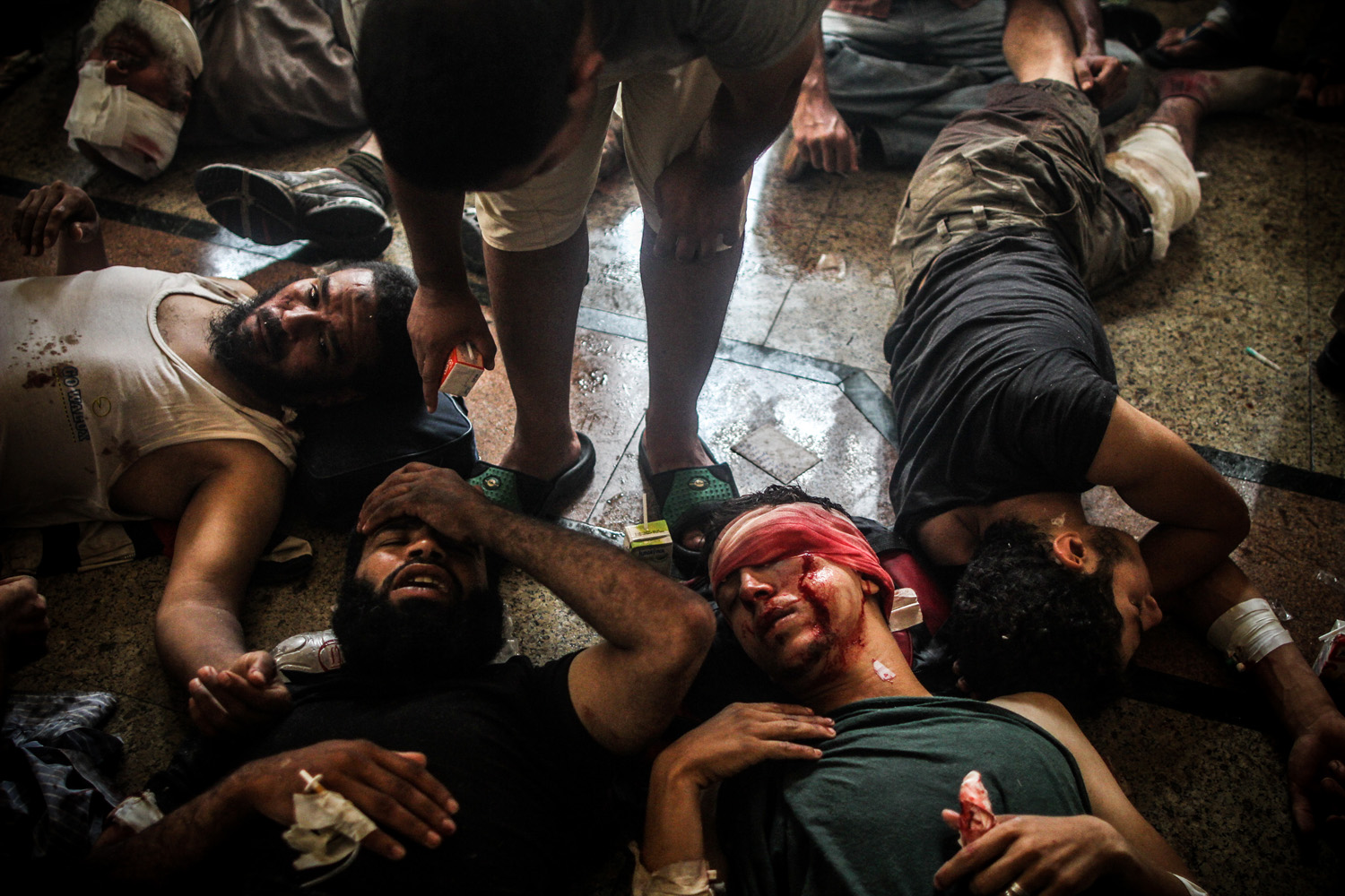 Aug. 14, 2013. A volunteer medic helps injured supporters of ousted president Mohamed Morsi who laid on the ground at a makeshift hospital during the violent dispersal of the camp by security forces.