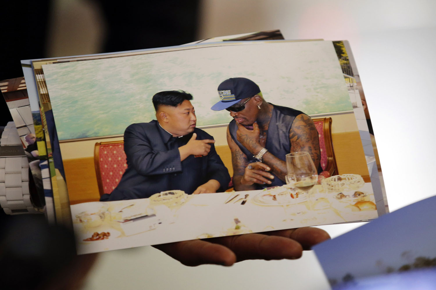 Former basketball star Rodman of the U.S. shows a picture which he took with North Korean leader Kim as he arrives at Beijing Capital International Airport