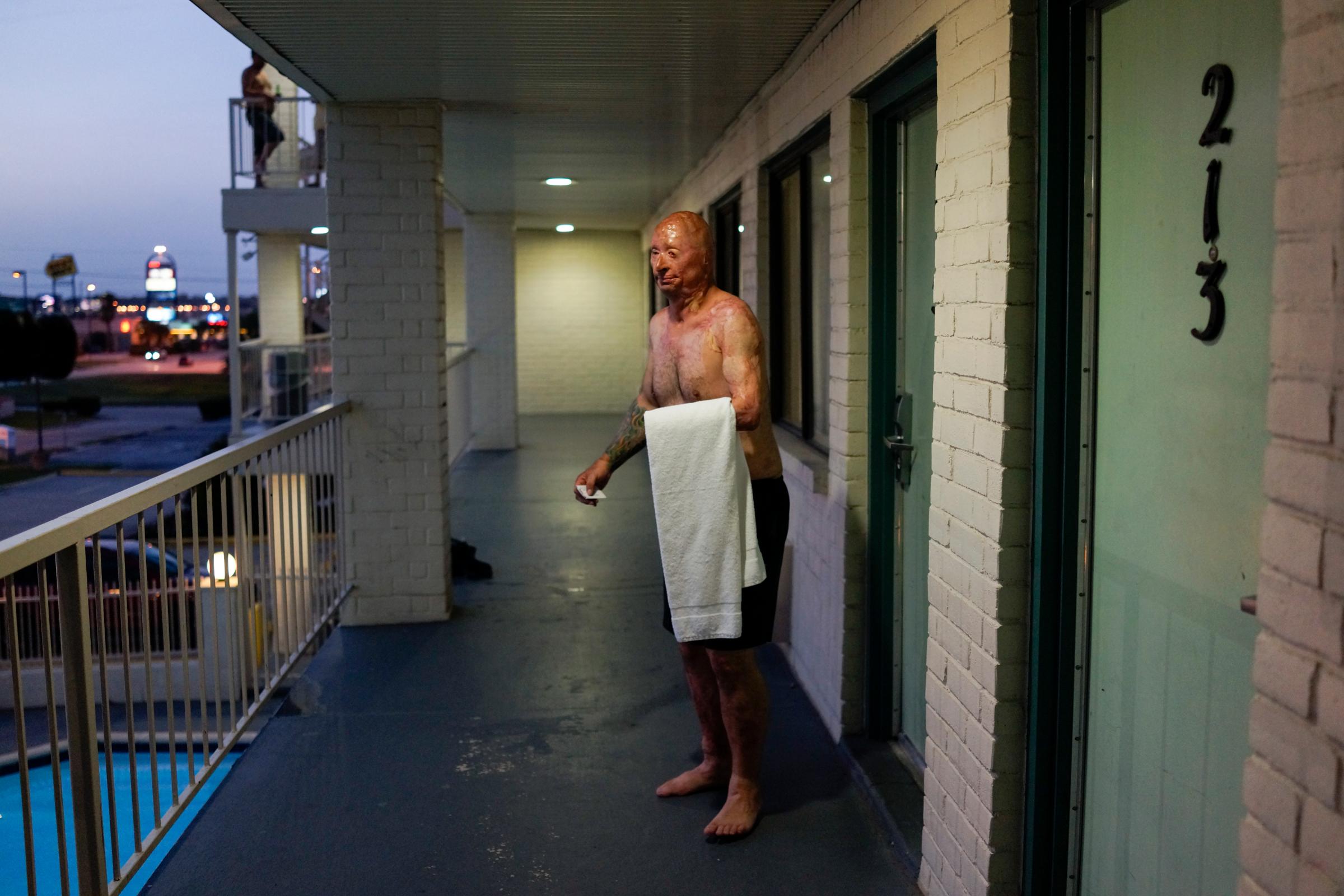 2013. Humble, TX. USA. Bobby steps out of his room to take a swim at a Motel 6 after visiting the father of Rodney McCandless. Rodney was killed in the IED explosion that injured Bobby. For years McCandless's family didn't know that anyone had survived the attack until Bobby was able to reach them by Facebook. It was their first meeting and Bobby wanted to pay his respects. Bobby Henline, 41, veteran of four tours to Iraq and sole survivor of an IED blast that killed the other four soldiers in his humvee in Iraq in 2007. He is now a standup comedian launching a new career with a routine built around his injuries. He received burns over 38% of his body in the blast.