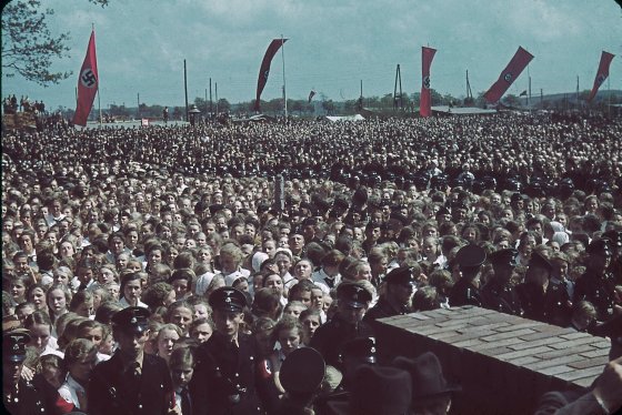 Crowds greet a saluting Adolf Hitler at a cornerstone ceremony at a Volkswagen factory, 1938.