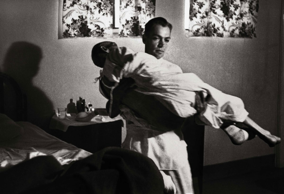 Dr. Ernest Ceriani gently carries an 85-year-old patient from a basement ward up to the operating room of the Kremmling, Colo., hospital, which had no elevator, 1948.