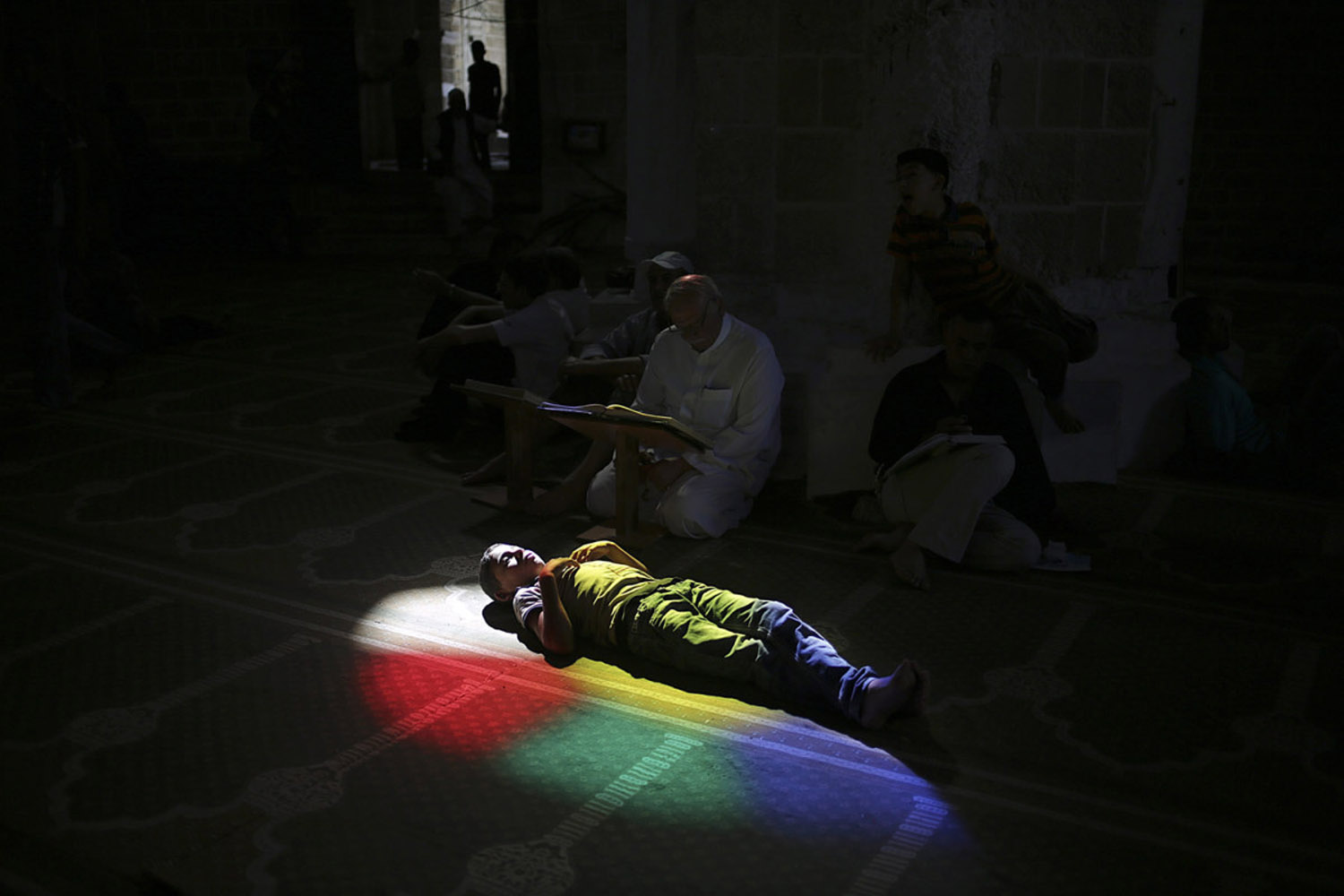July 11, 2013. A Palestinian child rests as others pray and read the Koran in a mosque during the holy month of Ramadan, in Gaza City, Gaza Strip.