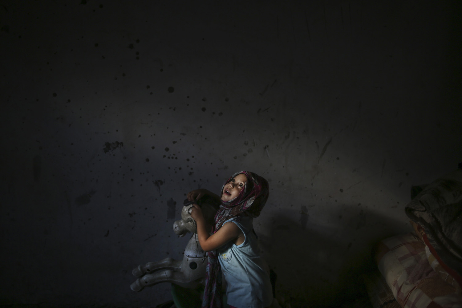 July 25, 2013. A Palestinian refugee girl, Nour Soboh, 4, plays with her toy horse in her family home in Bait Lahiya town, North Gaza Strip.