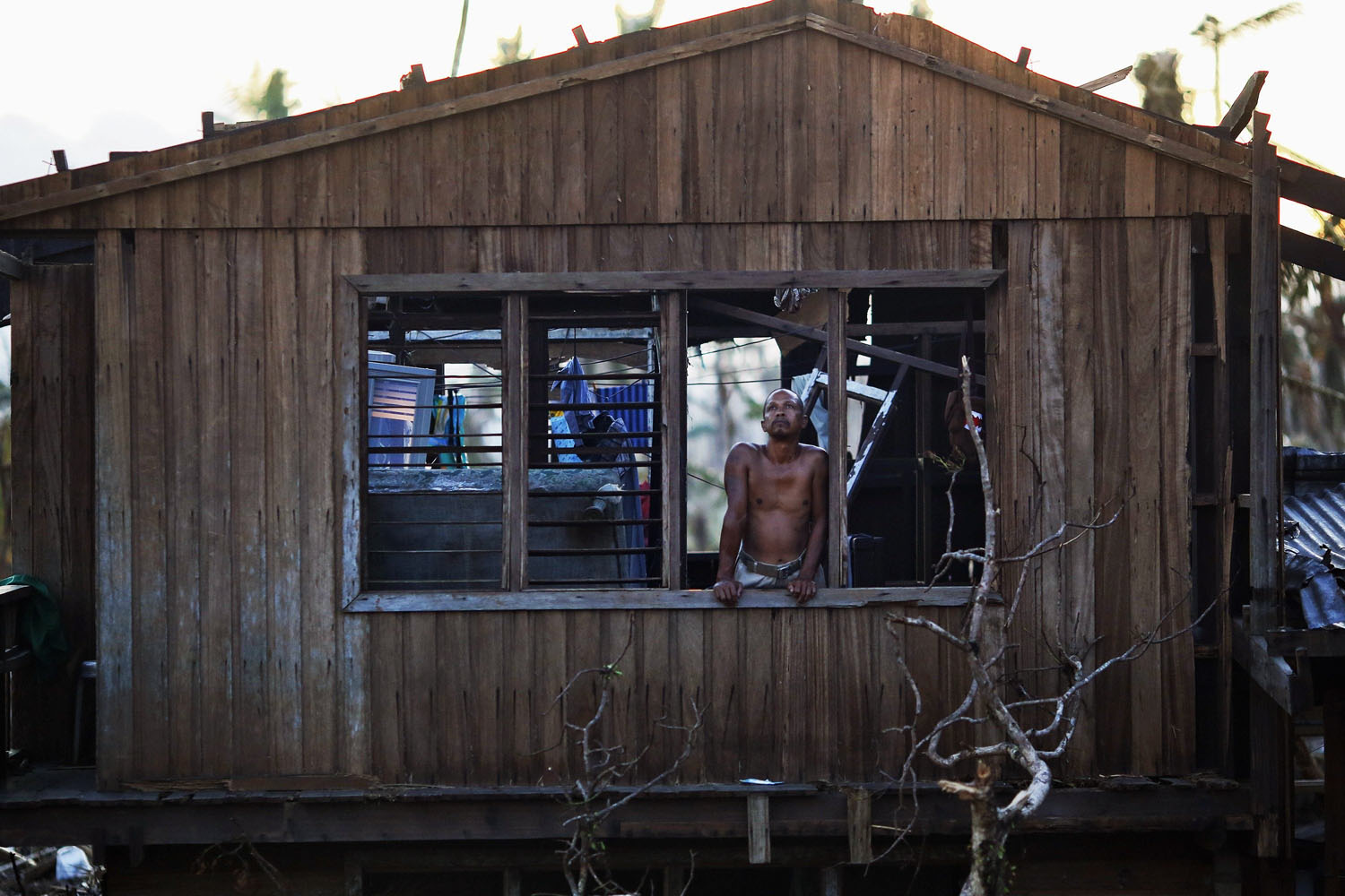 A survivor looks out from his home, which was damaged by Super Typhoon Haiyan, in Palo