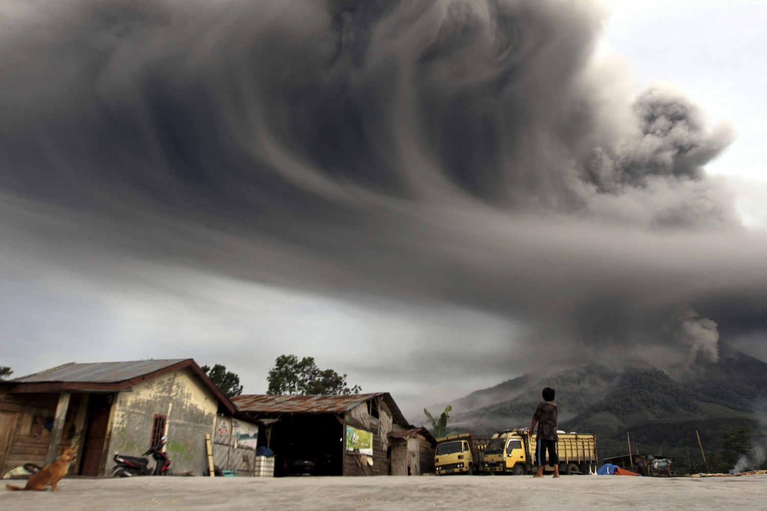 A woman looks on as Mount Sinabung spews ash, as pictured from Sibintun village in Karo district