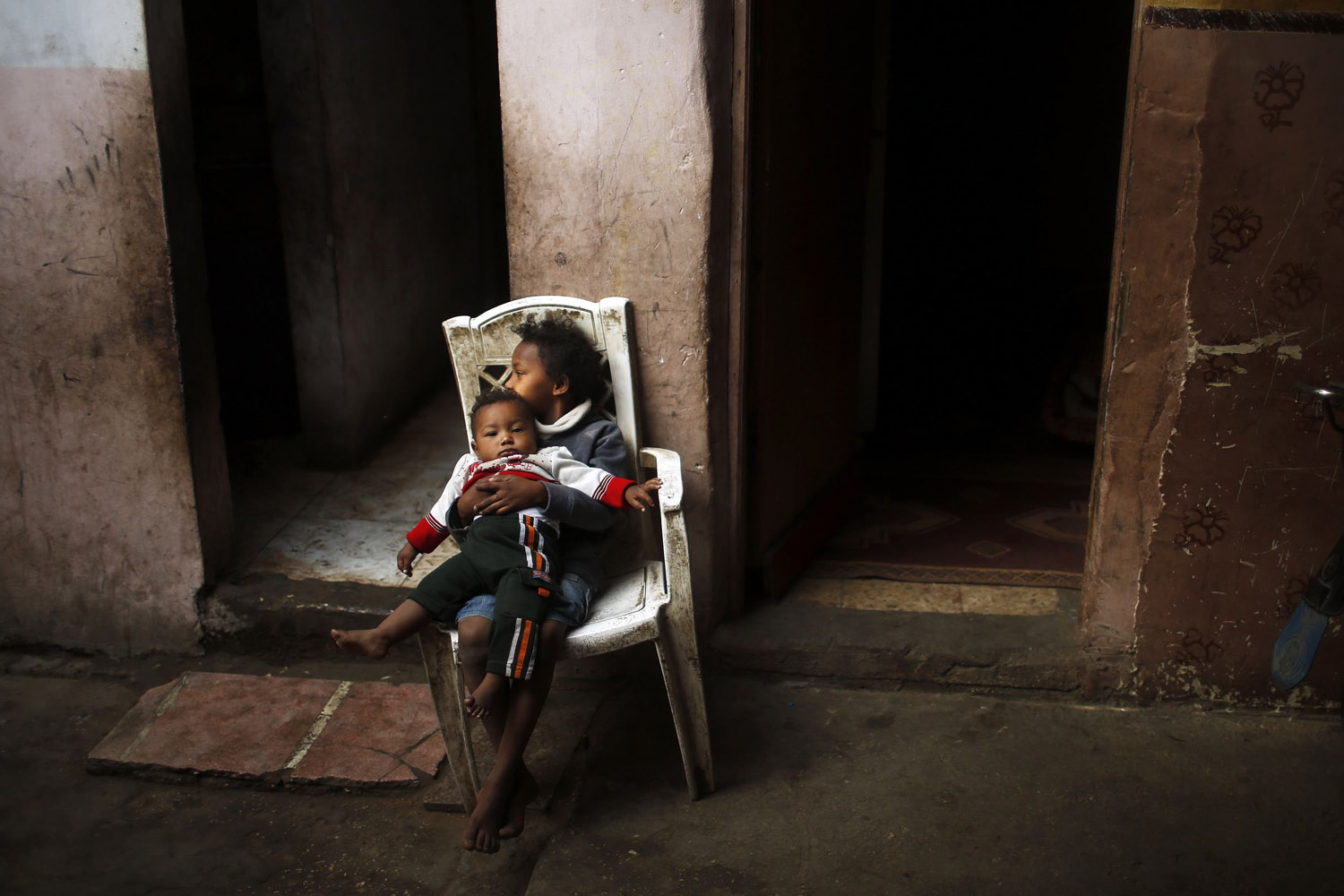 Nov. 18, 2013. A Palestinian girl holds her brother inside their family's dwelling in the northern Gaza Strip.