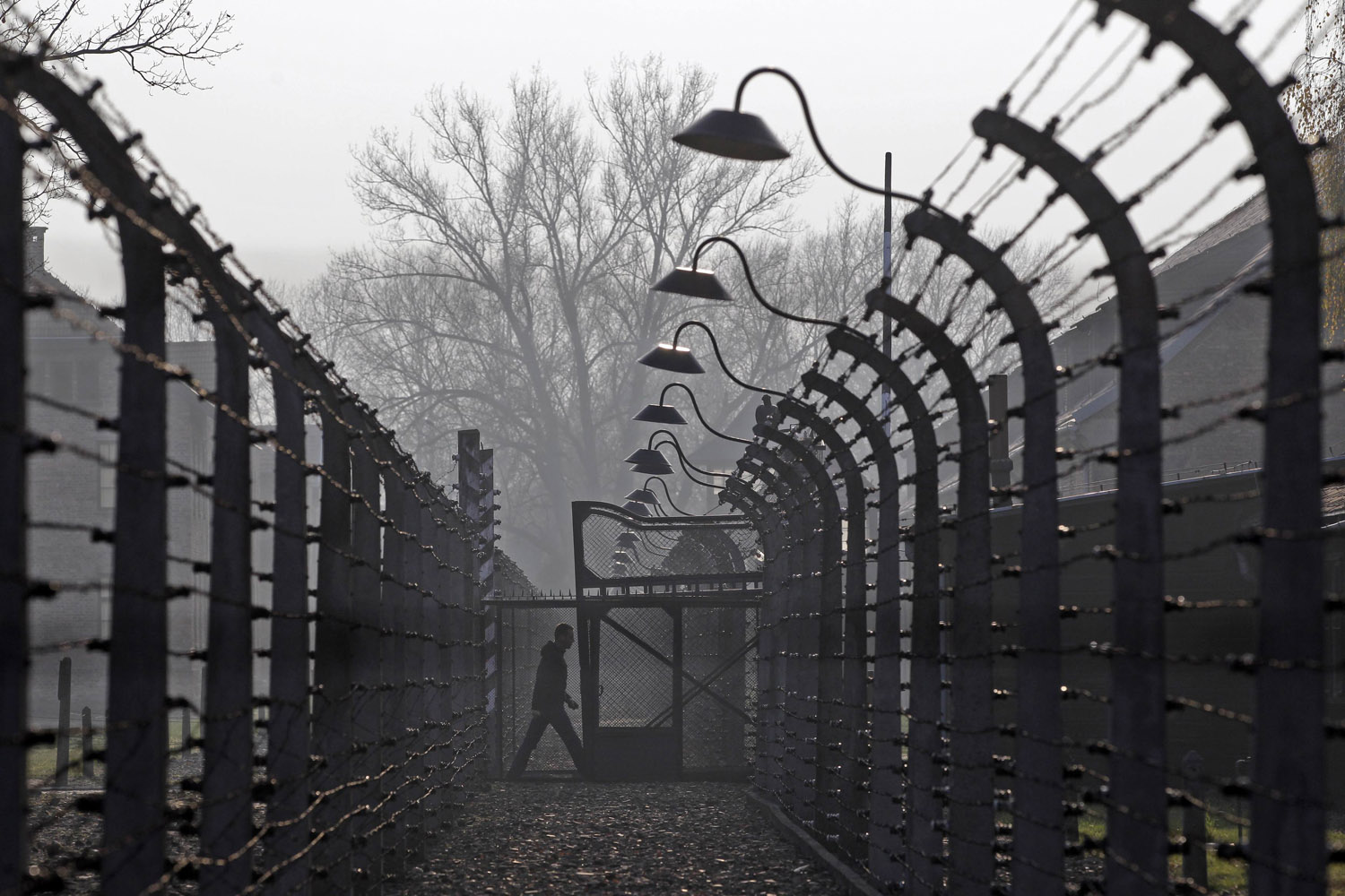 Nov. 18, 2013. A visitor walks between electric barbed-wired fences at the Auschwitz-Birkenau memorial and former concentration camp in Poland.