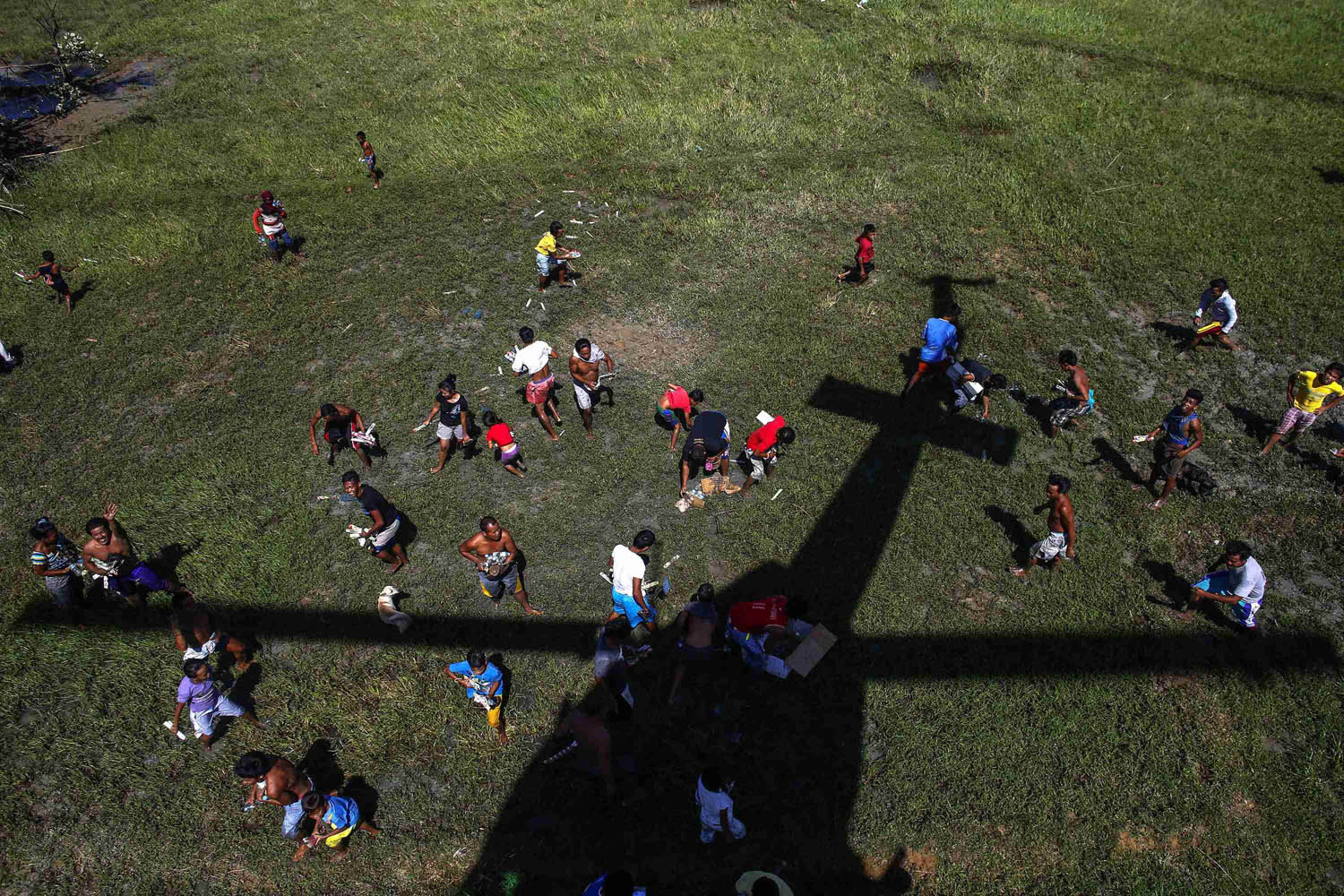 Survivors of Typhoon Haiyan rush to grab relief supplies as they are dropped by Philippine Air Forces helicopter at Barangay San Antonio
