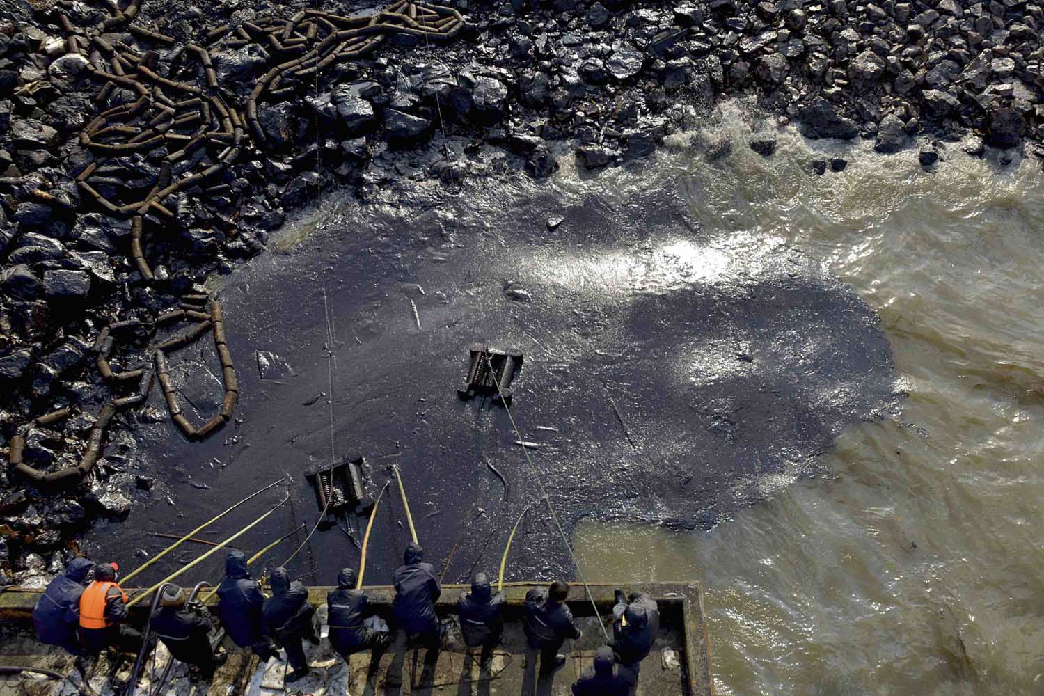 Workers clean up leaked oil after an oil pipeline explosion last week in Qingdao