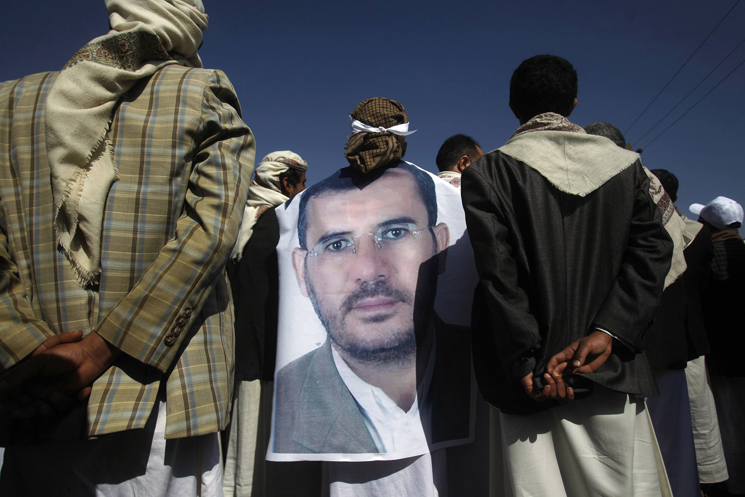 A mourner wears a poster of late Yemeni parliament member Jedban during his funeral in Sanaa