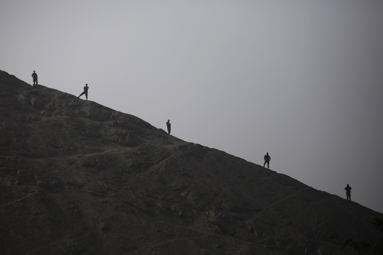 Anti-narcotics police officers guard on top of a hill near an oven during a drug incineration in Lima