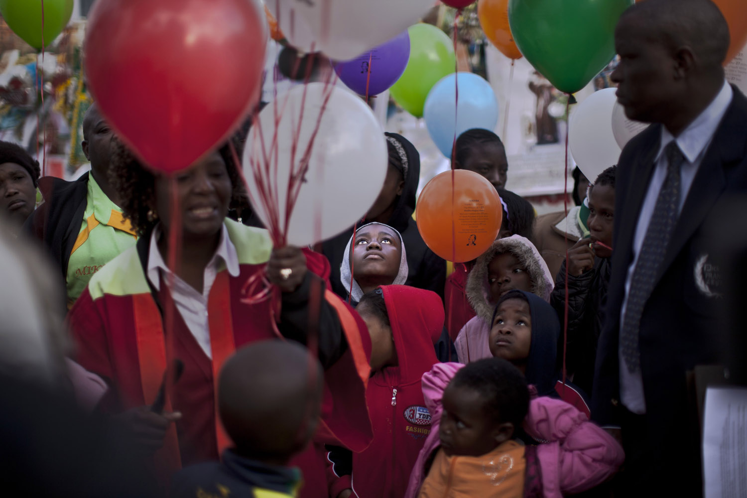 July 5, 2013. Children, a choir and other well-wishers hold balloons to release them to mark former South African President Nelson Mandela completing his 27th day in the hospital, correlating with the 27 years he spent in prison during the apartheid era, outside the Mediclinic Heart Hospital where he was being treated in Pretoria, South Africa.