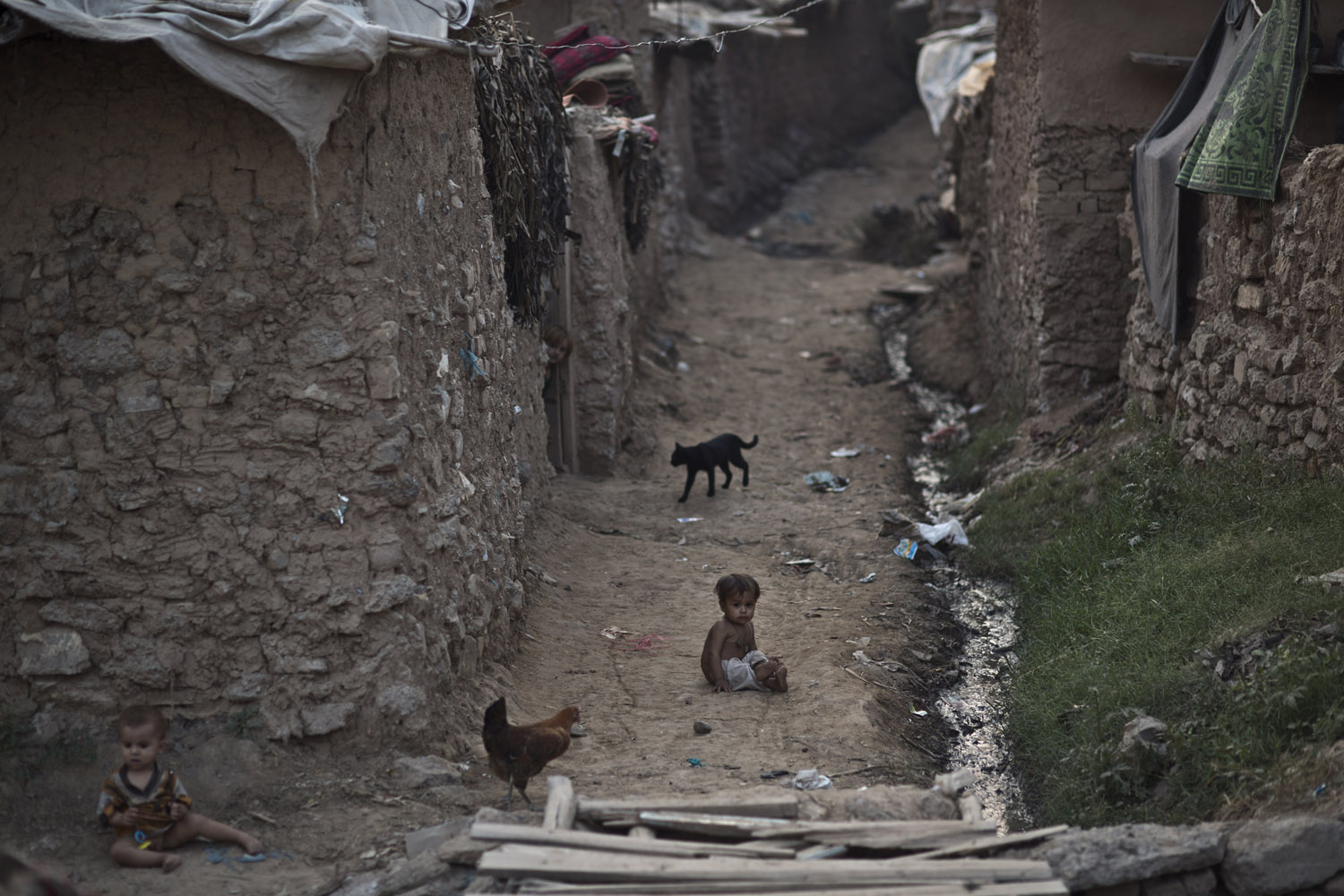 Oct. 10, 2013. Afghan refugee children play on the ground in an alley of a poor neighborhood on the outskirts of Islamabad.