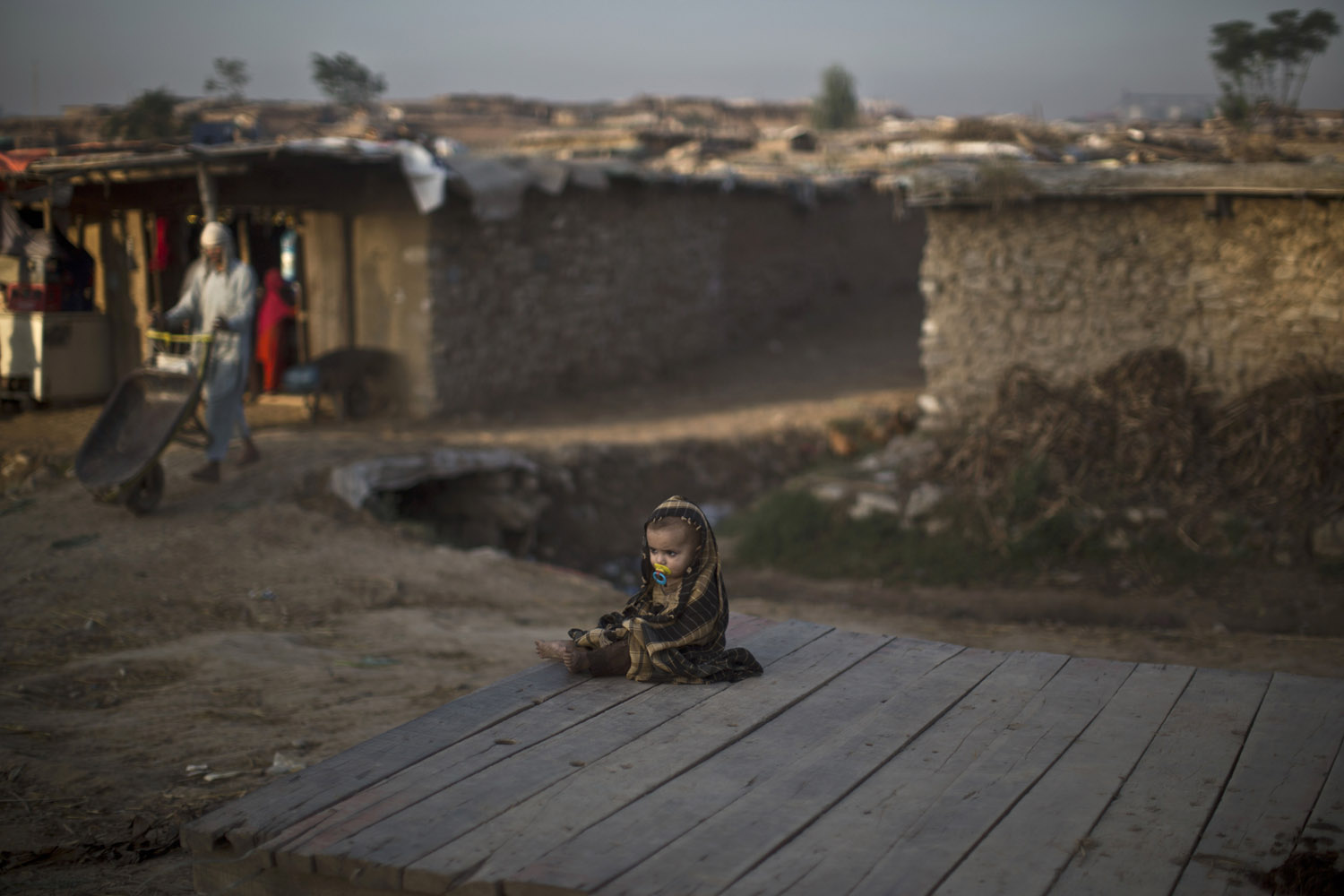 Oct. 14, 2013. An Afghan refugee child sits on roadside in a poor neighborhood on the outskirts of Islamabad.