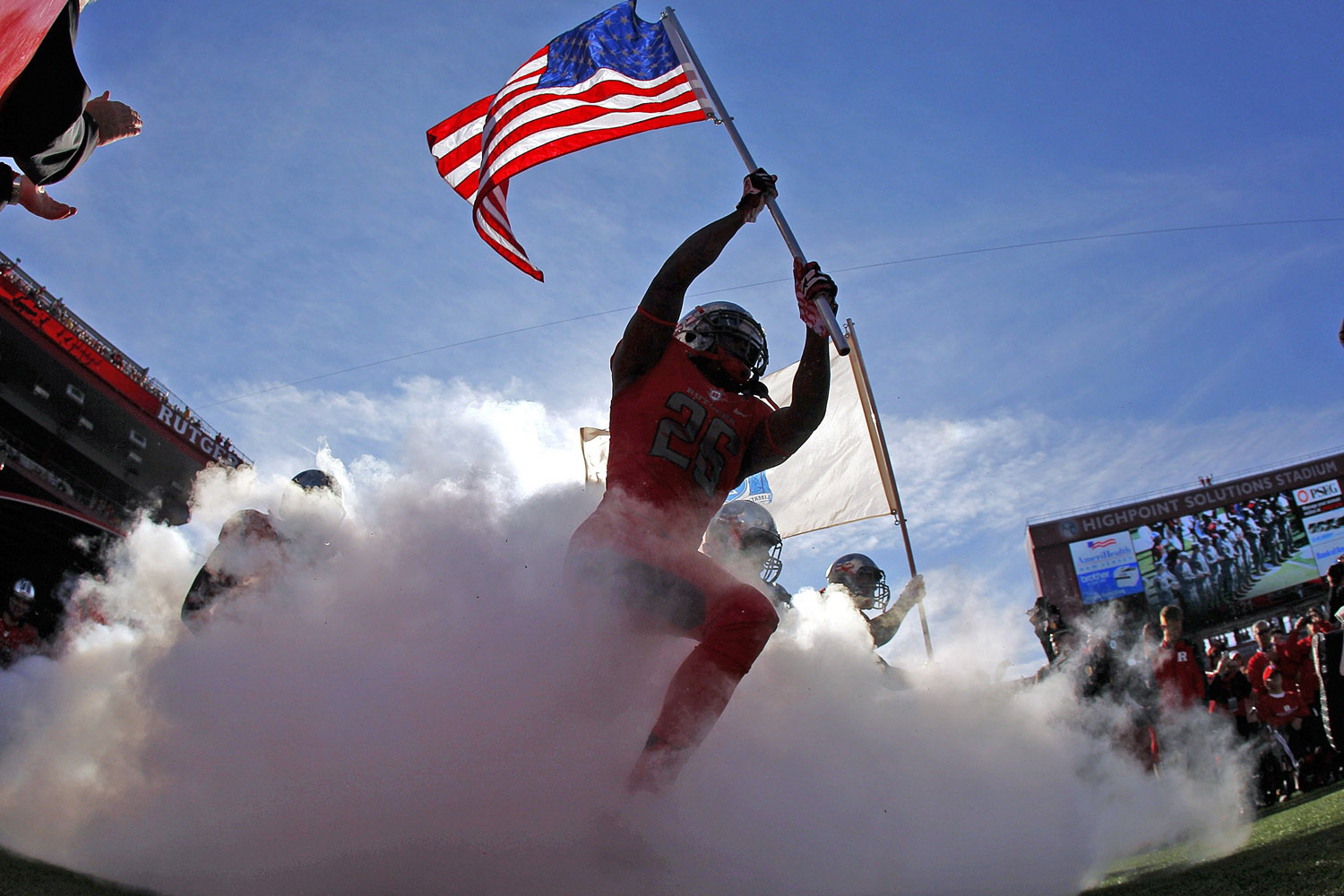 Nov. 16, 2013. Johnathan Aiken #26 of the Rutgers Scarlet Knights carries the American flag out as he leads his team onto the field before the start of their game against the Cincinnati Bearcats at High Point Solutions Stadium in Piscataway, N.J.