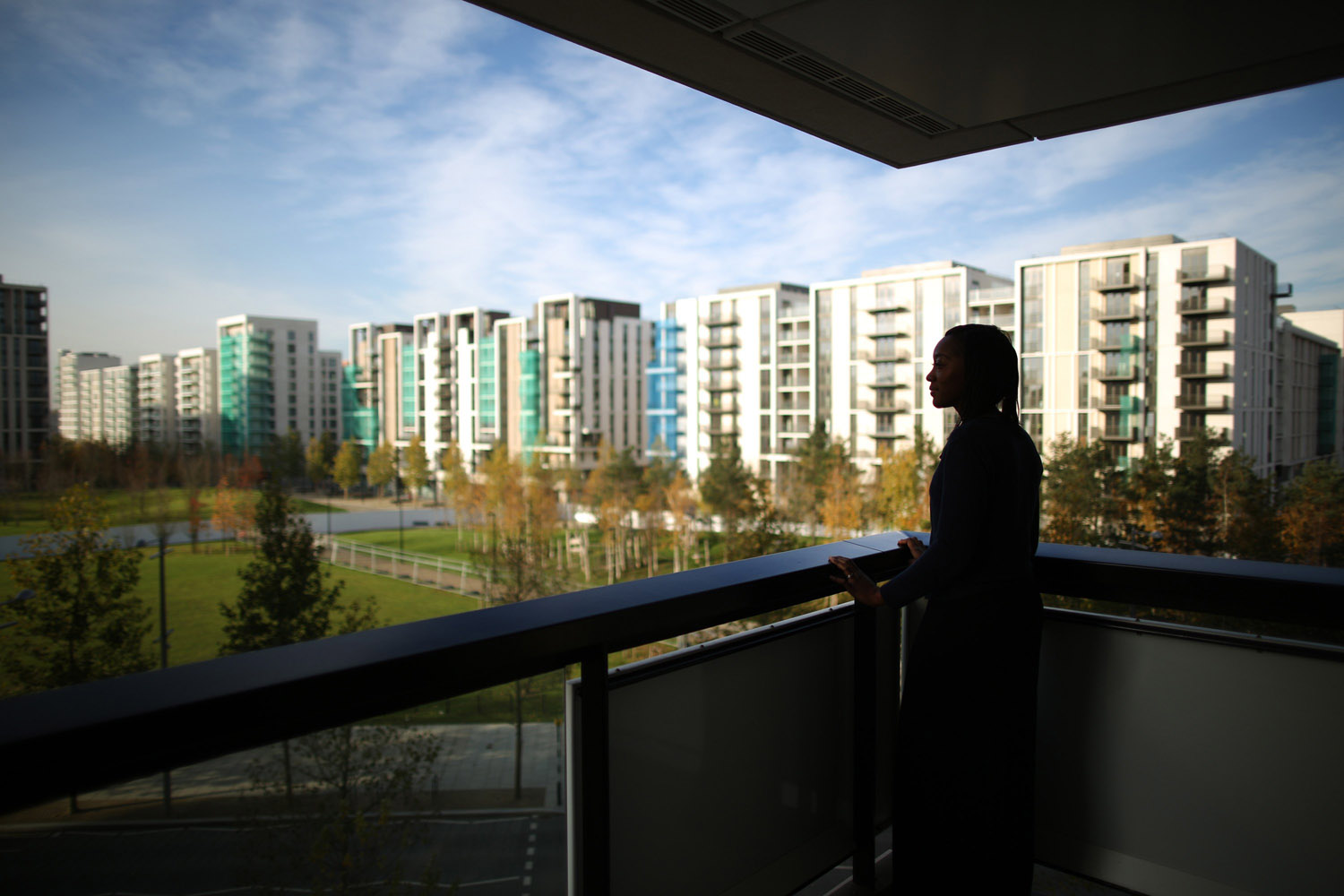Nov. 26, 2013. Resident Shardae Carr stands on her balcony at the newly transformed East Village near the Olympic Stadium in London.