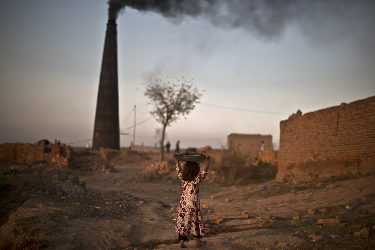 Nov. 21, 2013. Following her daily work with her parents at a brick factory, Pakistani Nagina Mohammed, 7, walks back to her home carrying coal over her head, that she collected to be used for heating and cooking, on the outskirts of Islamabad.