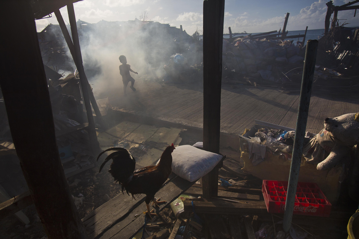 Nov. 15, 2013. A boy runs through the smoke of a cooking fire in the typhoon-shattered town of Guiuan, Philippines.