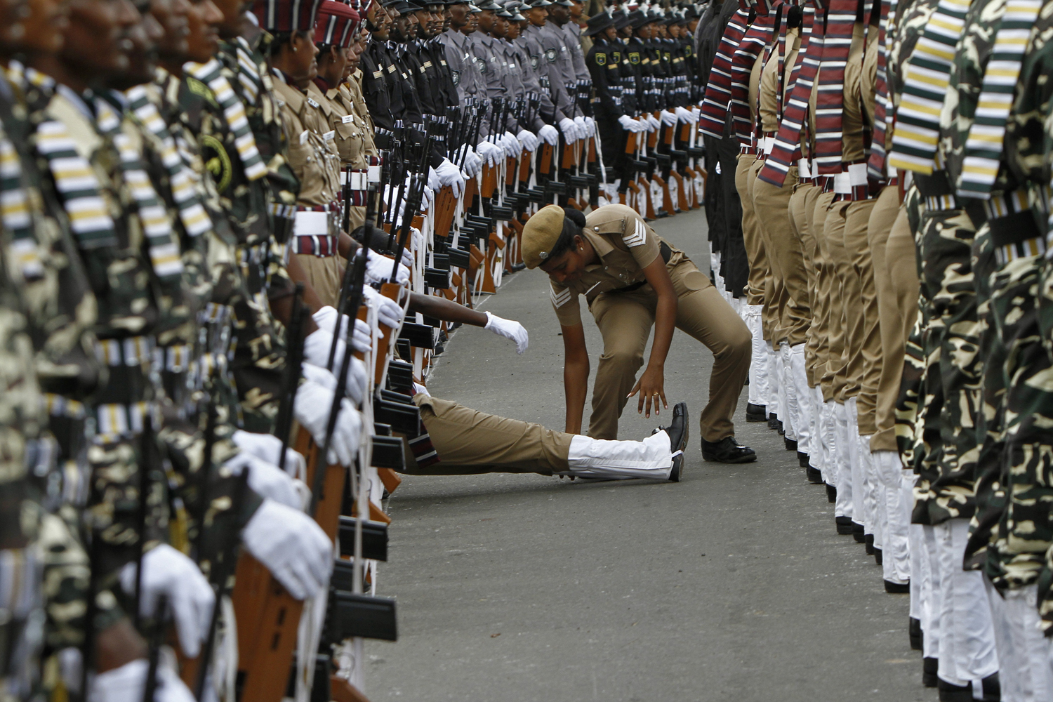 An Indian policewoman helps her comrade who fainted during the full-dress rehearsal for India's Independence Day celebrations in Chennai