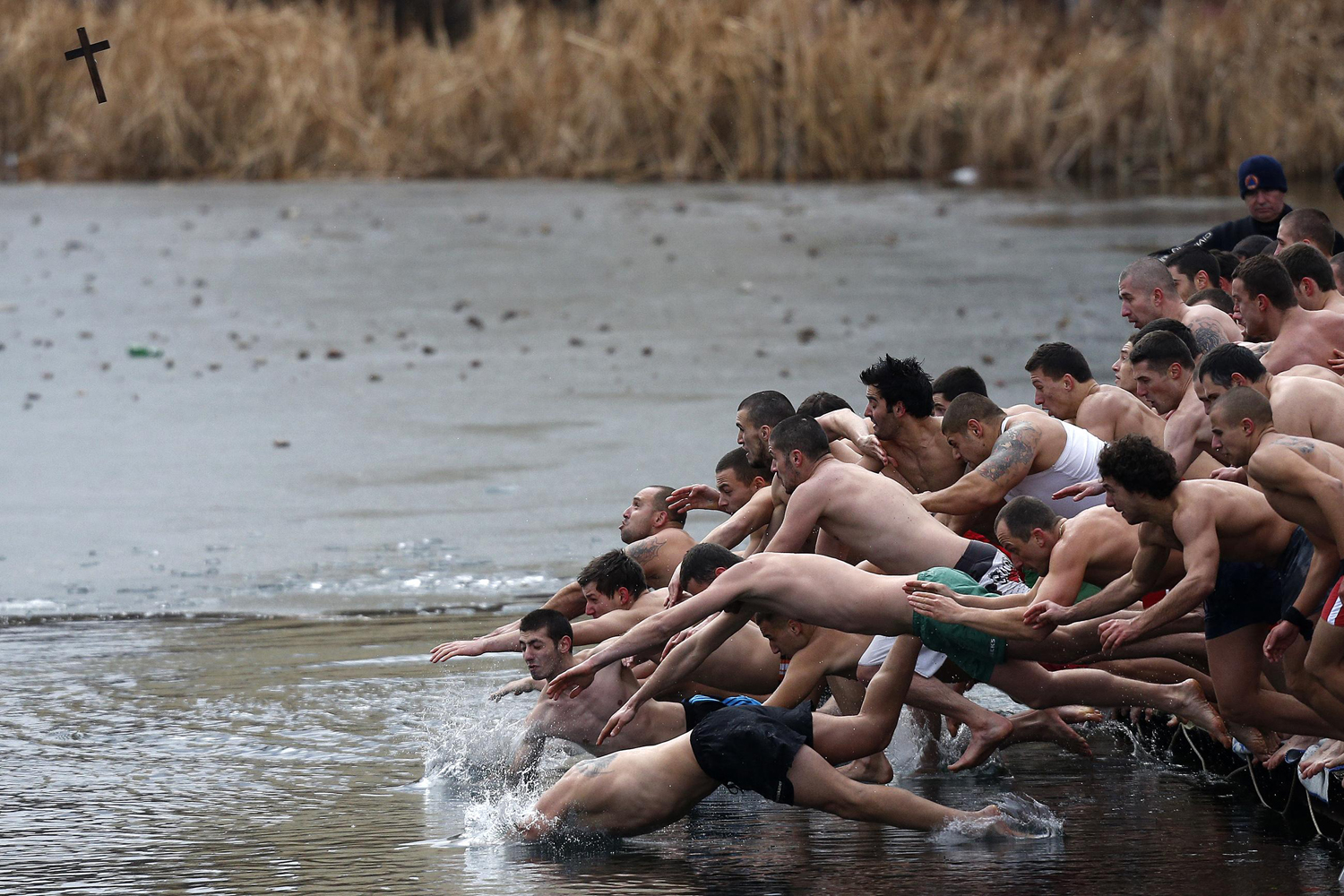 Men jump into the waters of a lake in an attempt to grab a wooden cross on Epiphany Day in Sofia