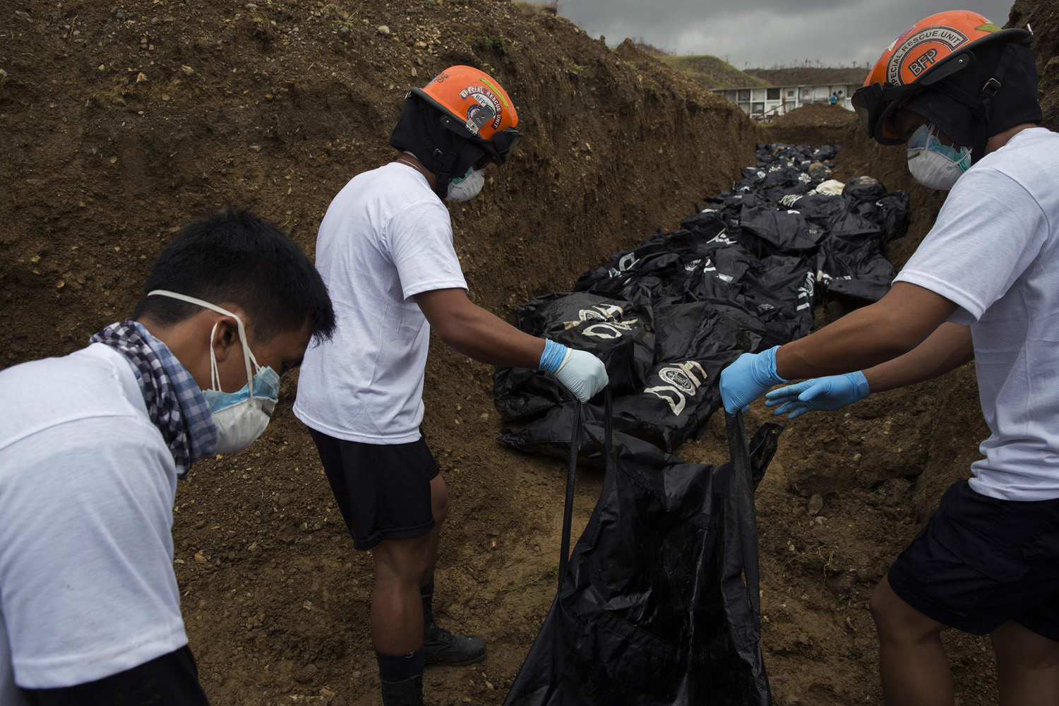 Rescue workers load body bags of people killed by Haiyan Typhoon into a mass grave in Tacloban, The Philippines on November 16, 2013.