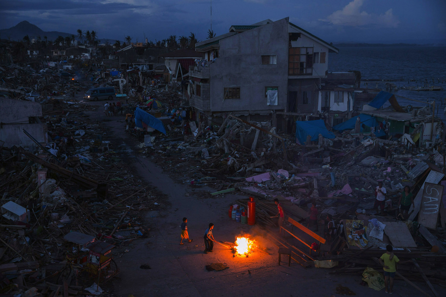 Nov. 16, 2013. People play by a fire in a neighborhood destroyed by Typhoon Haiyan in Tacloban, the Philippines.