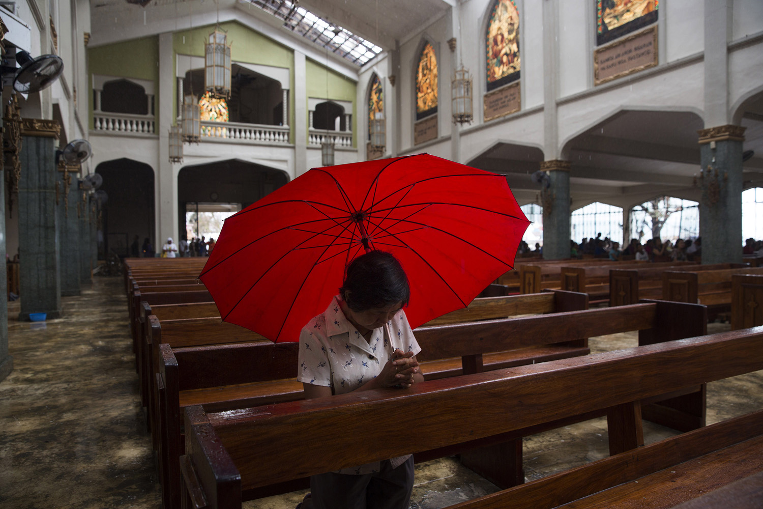 A woman preys during mass with an umbrella to protect herself from the rain coming in through the Santo Nino Church roof that was damaged by Haiyan Typhoon in Tacloban, The Philippines on November 17, 2013.