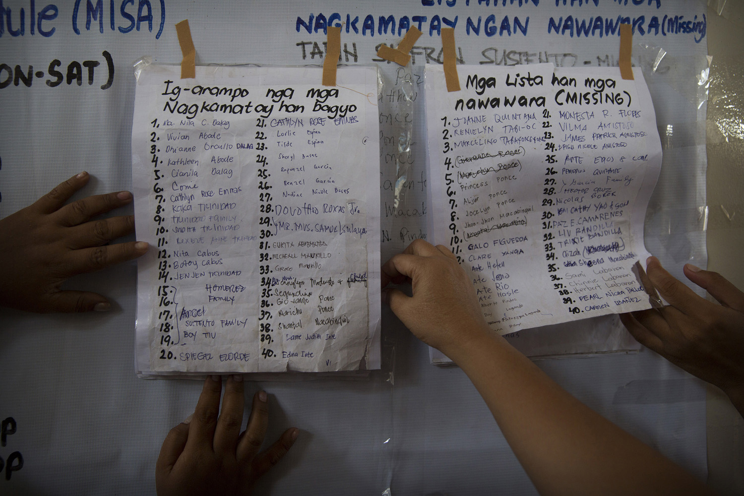 People search through lists of missing persons lost in Haiyan Typhoon in Tacloban, The Philippines on November 17, 2013.