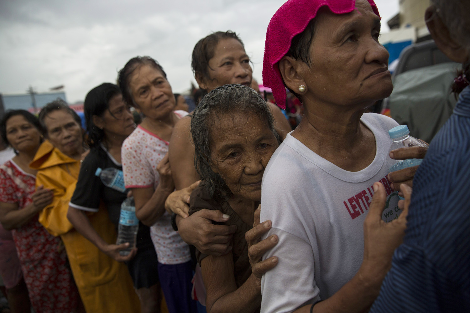 Displaced people effected by Haiyan Typhoon queue in the rain for the first aid delivery at a displacement camp in Tacloban, The Philippines on November 14, 2013.