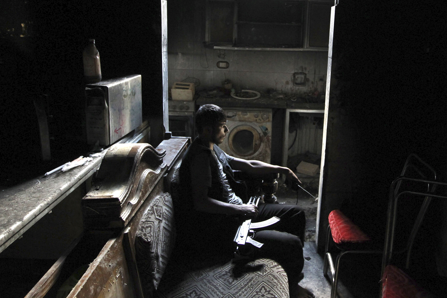 A member of the Free Syrian Army sits with his weapon inside a house in Aleppo's al-Sayyid Ali neighborhood