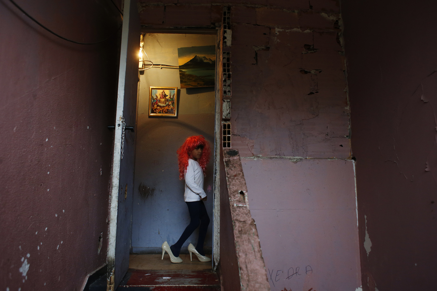 Antonio Acuna plays dress up with a wig and high heel shoes at the factory where he lives with his family after the postponement of the demolition of their homes in Madrid