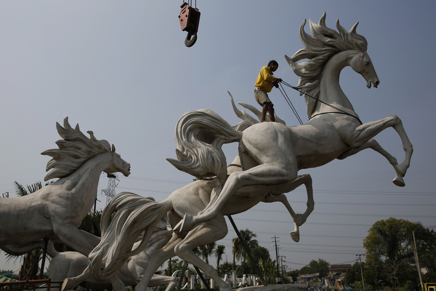 Worker tightens a rope to raise a four-metre-high statue of horses at a new housing complex in Bogor