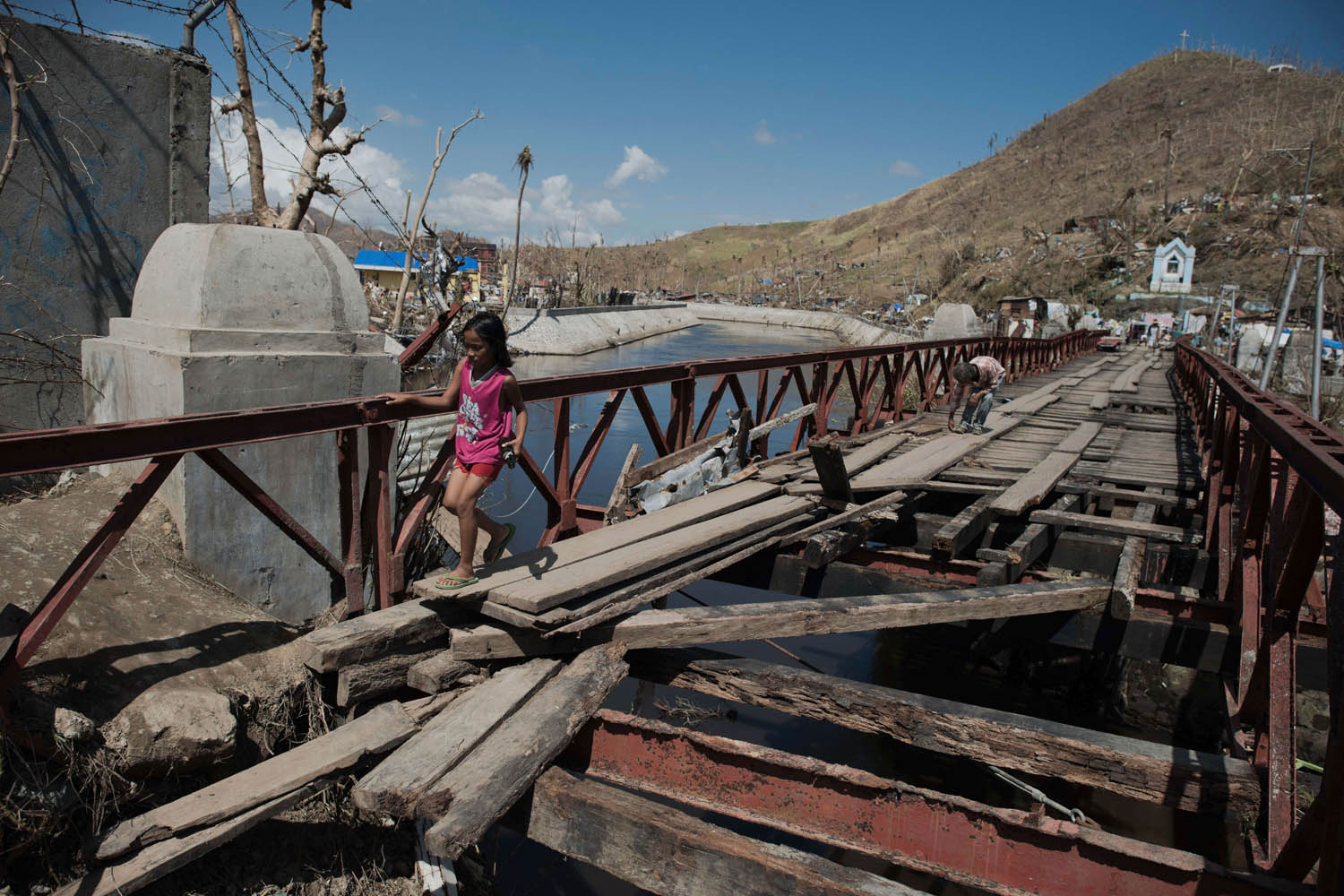 Nov. 18, 2013. A typhoon victim crosses a damaged bridge bridge in Palo, the Philippines.