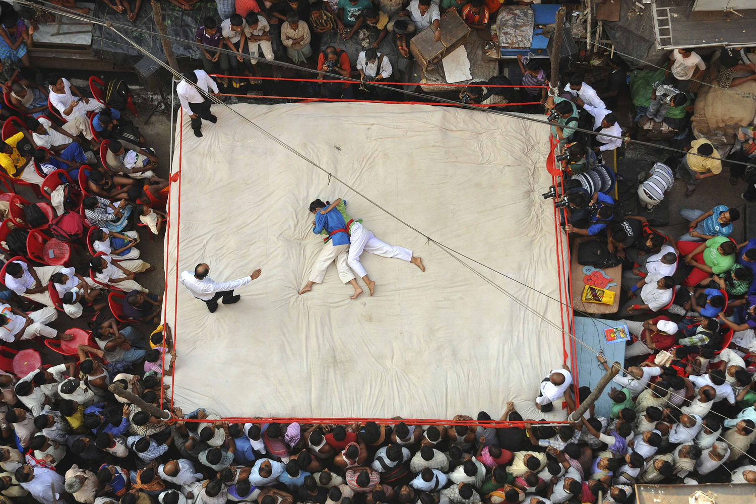Wrestlers fight during an amateur wrestling match inside a makeshift ring built on a road junction in Kolkata