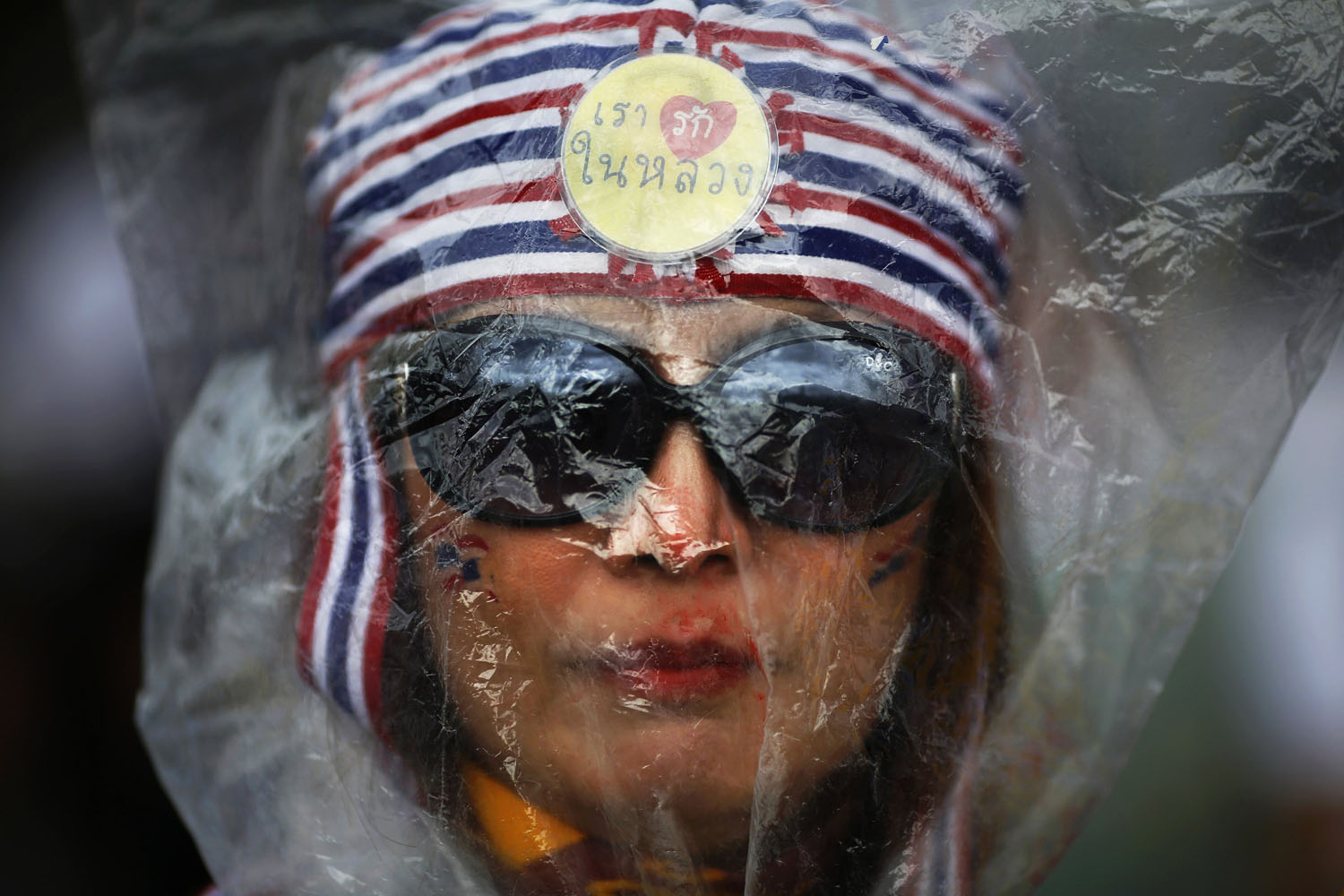 A protester against an amnesty bill wears a plastic bag over her head in front of police barricades on the main road near the government and parliament buildings in central Bangkok