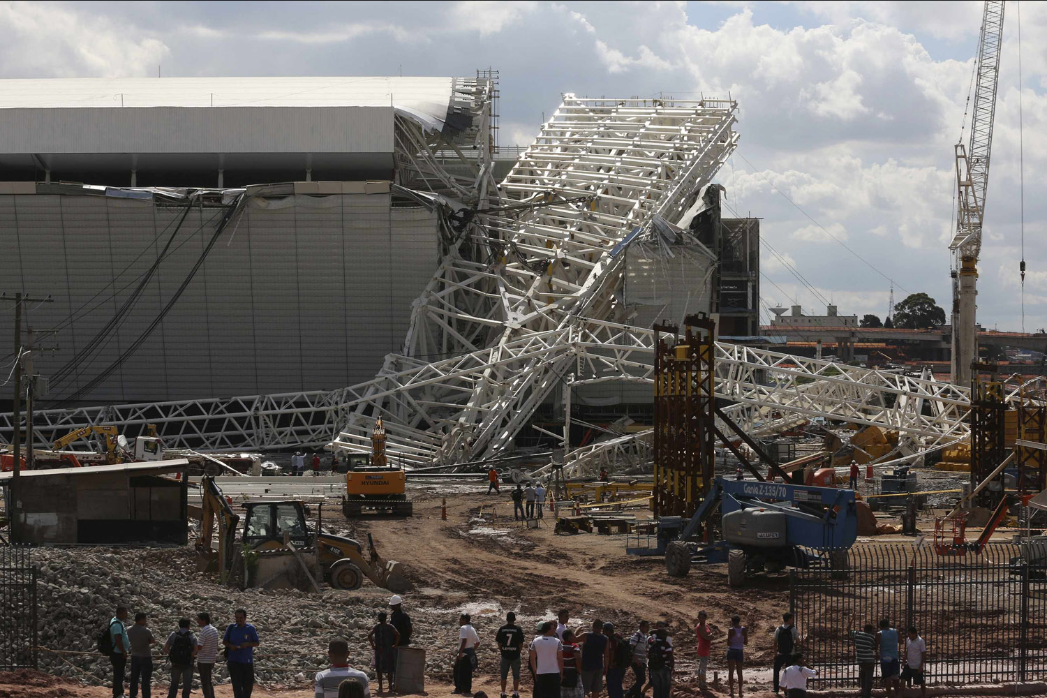 Workers stand near a crane that collapsed on the site of the Arena Sao Paulo stadium, known as "Itaquerao", which will host the opening soccer match of the 2014 World Cup, in Sao Paulo